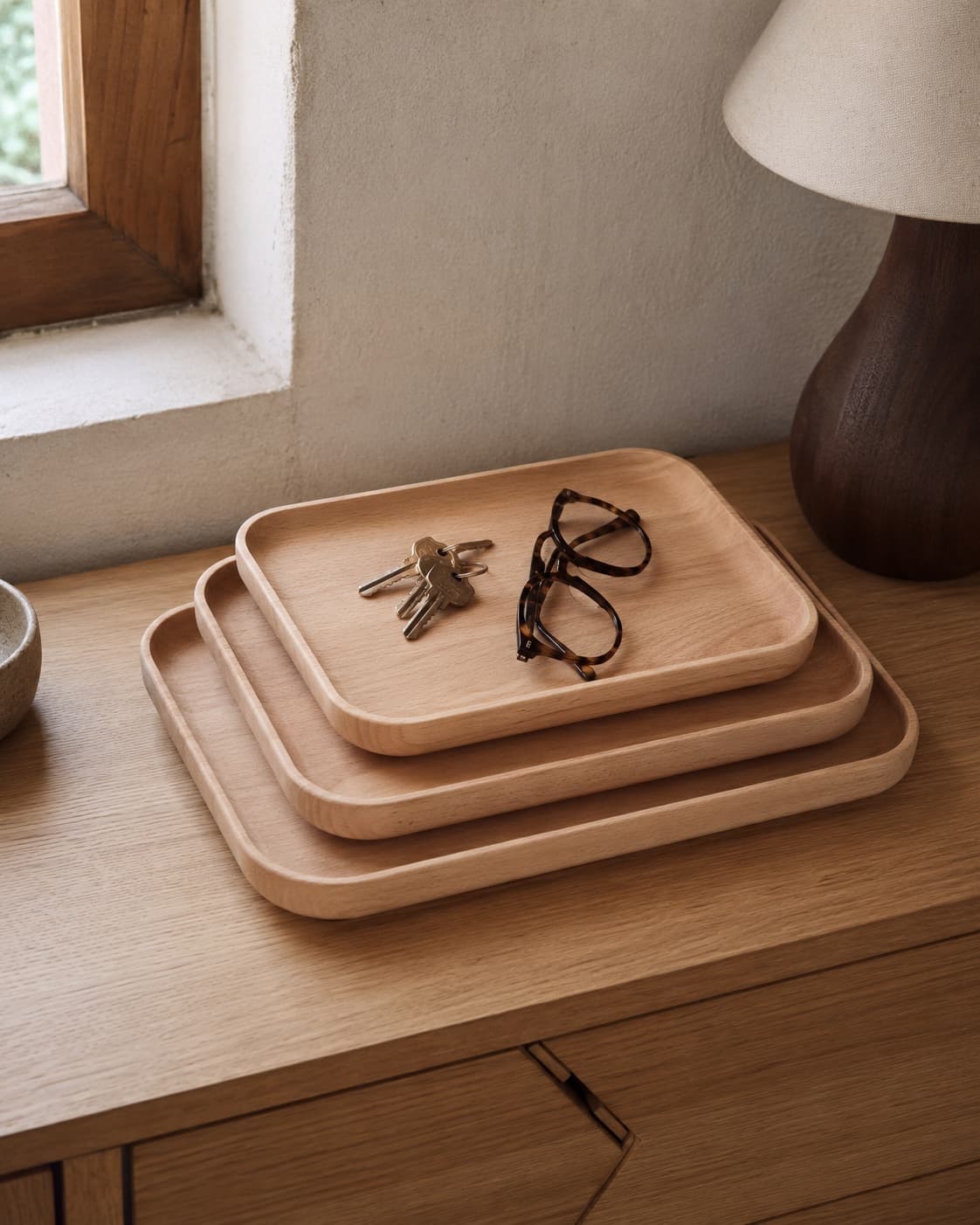 Three graduated solid wood trays arranged on a bedside surface